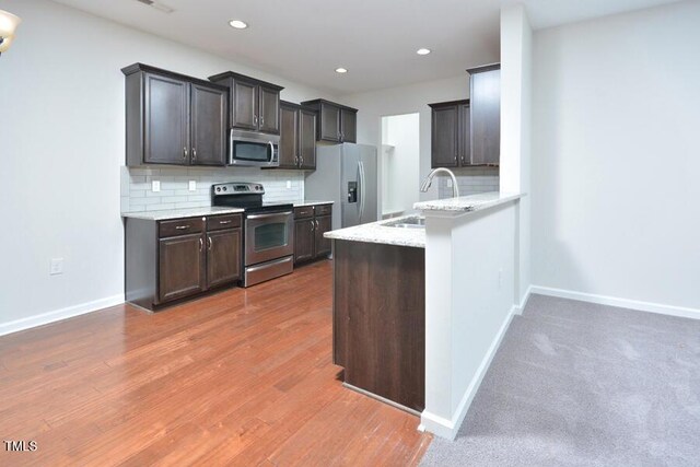 321 Westgrove Ct, Durham, NC 27703 - kitchen featuring stainless steel appliances, decorative backsplash, a peninsula, dark brown cabinetry, and recessed lighting