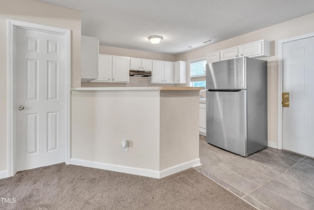 5617 Tealbrook Dr, Raleigh, NC 27610 - kitchen with freestanding refrigerator, white cabinets, light countertops, under cabinet range hood, and a peninsula