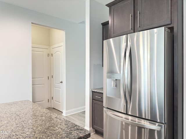 13 Knotty Pine Ln, Clayton, NC 27520 - kitchen with stainless steel refrigerator with ice dispenser, light wood-type flooring, dark brown cabinetry, stone counters, and baseboards