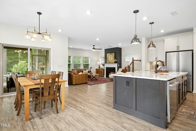 137 Azalea View Way, Holly Springs, NC 27540 - kitchen with appliances with stainless steel finishes, light wood-style flooring, light countertops, a lit fireplace, and an island with sink