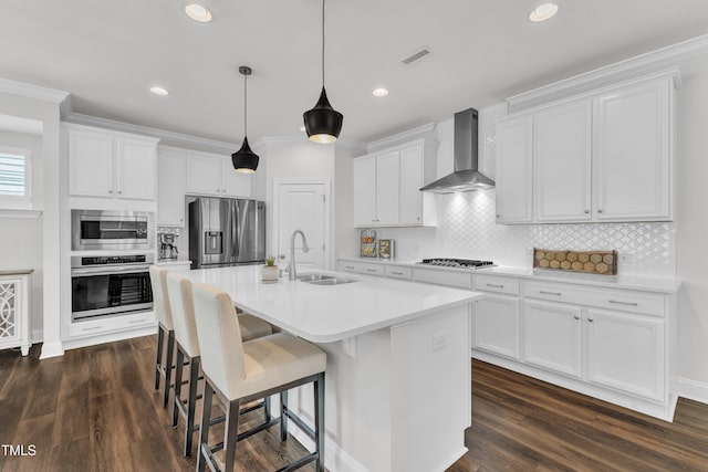 2969 Thirlestane Dr, Apex, NC 27502 - kitchen featuring appliances with stainless steel finishes, wall chimney range hood, white cabinets, backsplash, and a center island with sink