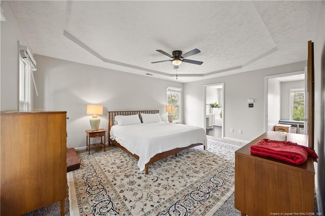 3517 Gables Dr, Fayetteville, NC 28311 - bedroom with a tray ceiling, multiple windows, a textured ceiling, baseboards, and ceiling fan