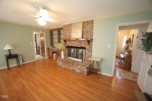 6717 Valley Dr, Raleigh, NC 27612 - living area featuring crown molding, light wood-style flooring, a ceiling fan, a textured ceiling, and a brick fireplace