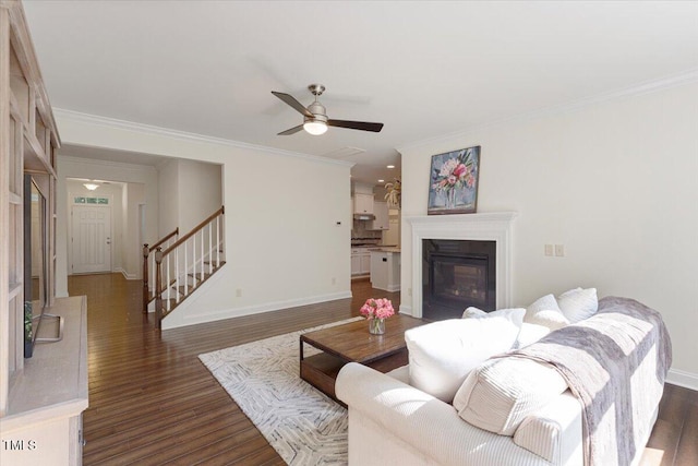 531 Finnbar Dr, Cary, NC 27519 - living area featuring dark wood-style flooring, ornamental molding, stairs, ceiling fan, and a glass covered fireplace