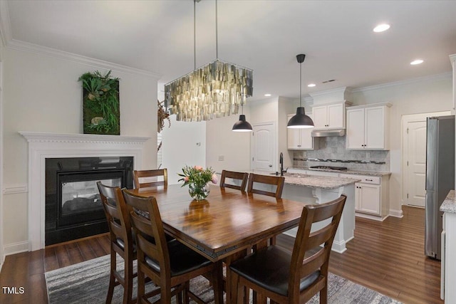 531 Finnbar Dr, Cary, NC 27519 - dining room with dark wood-style flooring, a multi sided fireplace, ornamental molding, a chandelier, and recessed lighting