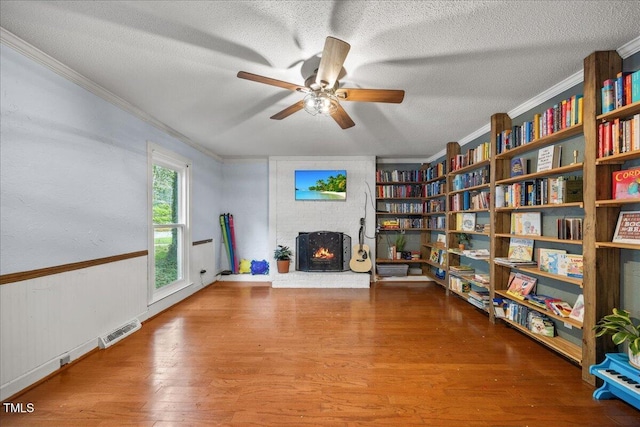 1013 Oak Forest Dr NW, Wilson, NC 27896 - sitting room with ornamental molding, a textured ceiling, a brick fireplace, wood finished floors, and a ceiling fan