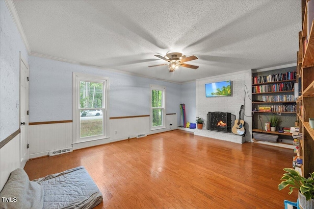 1013 Oak Forest Dr NW, Wilson, NC 27896 - living area featuring a textured ceiling, a brick fireplace, a ceiling fan, healthy amount of natural light, and wood finished floors