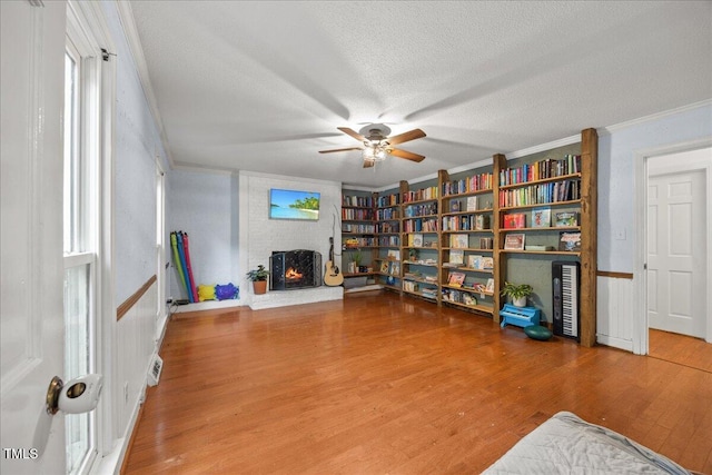 1013 Oak Forest Dr NW, Wilson, NC 27896 - sitting room with ornamental molding, wood finished floors, a fireplace, ceiling fan, and a textured ceiling