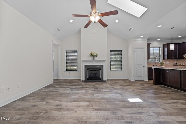801 Socata Ln, Mebane, NC 27302 - unfurnished living room with ceiling fan, recessed lighting, a fireplace with flush hearth, a skylight, and wood finished floors