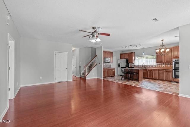 760 Stackhurst Way, Wake Forest, NC 27587 - unfurnished living room featuring wood finished floors, ceiling fan, a chandelier, stairway, and a textured ceiling
