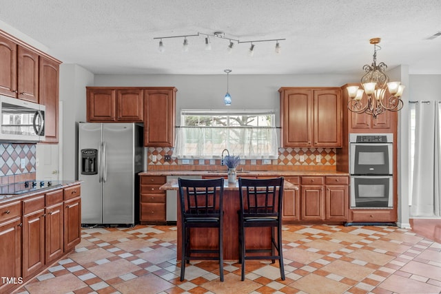 760 Stackhurst Way, Wake Forest, NC 27587 - kitchen featuring appliances with stainless steel finishes, a chandelier, brown cabinets, light countertops, and backsplash