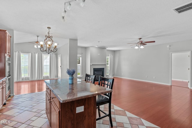 760 Stackhurst Way, Wake Forest, NC 27587 - kitchen with ceiling fan, a breakfast bar area, a kitchen island, a glass covered fireplace, and open floor plan