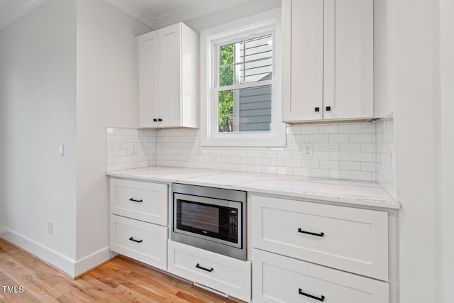 414 Wyndham Dr, Chapel Hill, NC 27516 - kitchen with stainless steel microwave, light wood-style flooring, ornamental molding, light stone countertops, and white cabinets