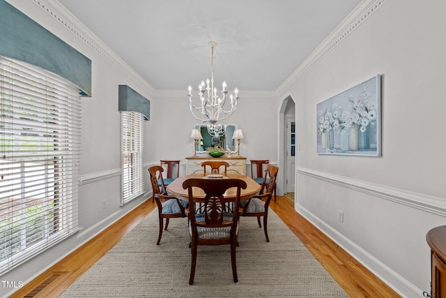 8004 Gabriels Bend Dr, Raleigh, NC 27612 - dining area featuring a chandelier, light wood finished floors, arched walkways, and crown molding