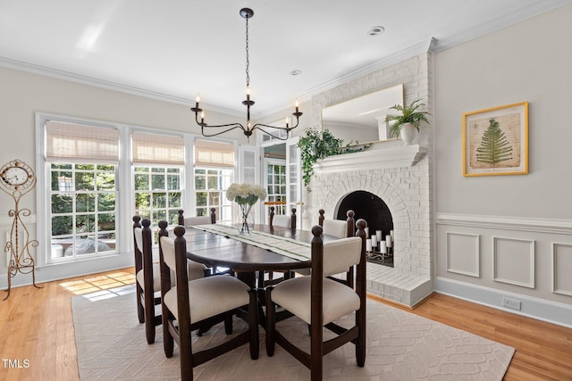 8004 Gabriels Bend Dr, Raleigh, NC 27612 - dining room with a chandelier, crown molding, light wood-type flooring, and a fireplace