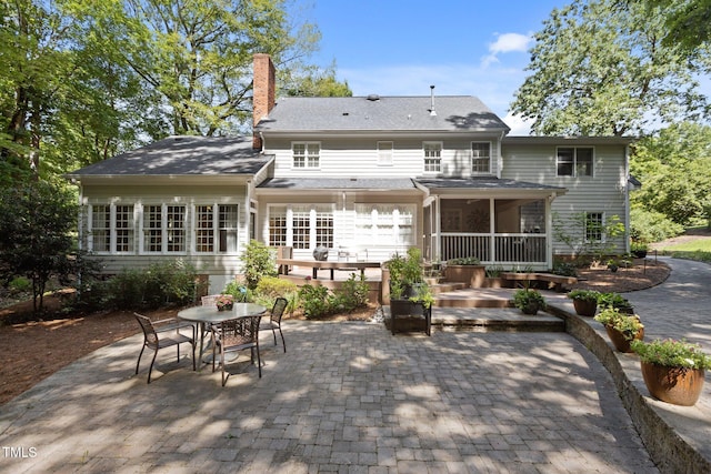 8004 Gabriels Bend Dr, Raleigh, NC 27612 - back of property with a patio, a sunroom, a chimney, and outdoor dining area