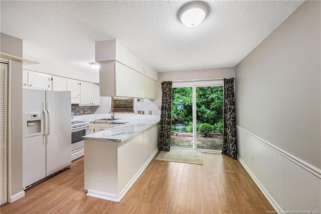 1255 Donaldson Ct, Cary, NC 27511 - kitchen with white appliances, a peninsula, white cabinets, light wood-style flooring, and a textured ceiling