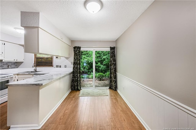 1255 Donaldson Ct, Cary, NC 27511 - kitchen featuring electric range, a peninsula, light wood-style flooring, white cabinetry, and a textured ceiling
