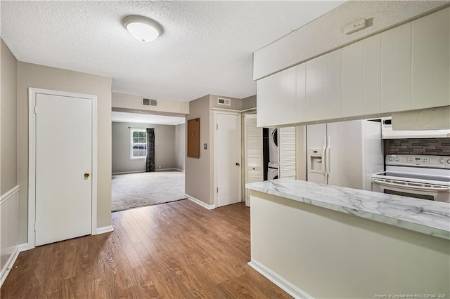1255 Donaldson Ct, Cary, NC 27511 - kitchen featuring white appliances, stacked washer / drying machine, wood finished floors, a textured ceiling, and baseboards