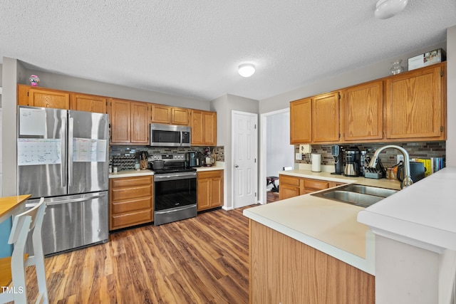 304 Gold Point Dr, Cary, NC 27519 - kitchen featuring appliances with stainless steel finishes, wood finished floors, light countertops, decorative backsplash, and a textured ceiling