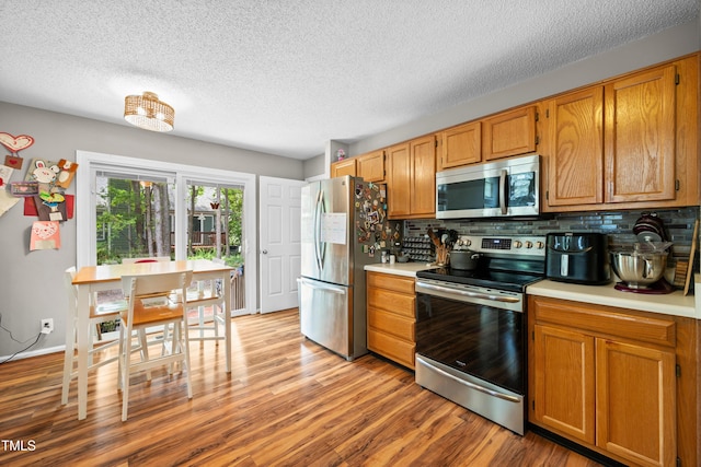 304 Gold Point Dr, Cary, NC 27519 - kitchen with stainless steel appliances, light countertops, decorative backsplash, a textured ceiling, and light wood-style floors
