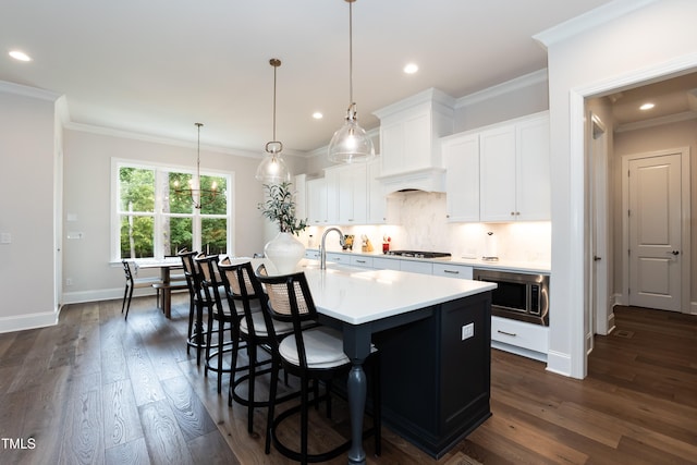 4104 Green Chase Way, Apex, NC 27539 - kitchen featuring gas stovetop, stainless steel microwave, a kitchen island with sink, light countertops, and ornamental molding