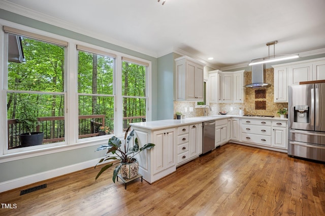 105 Gorge Ct, Cary, NC 27518 - kitchen with stainless steel appliances, wall chimney range hood, healthy amount of natural light, light countertops, and ornamental molding