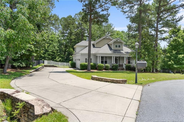 951 Whispering Pines Dr, Spring Lake, NC 28390 - bungalow with covered porch, concrete driveway, an attached garage, and view of wooded area
