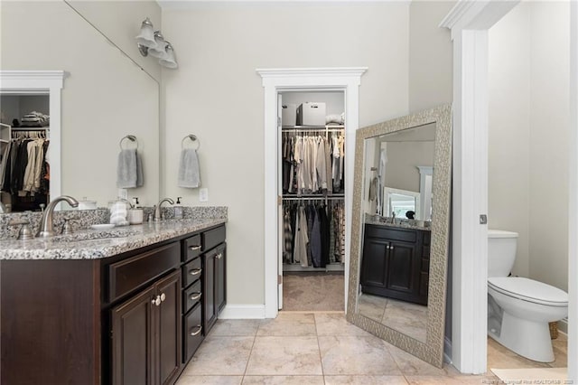 951 Whispering Pines Dr, Spring Lake, NC 28390 - bathroom with double vanity, a walk in closet, toilet, and baseboards