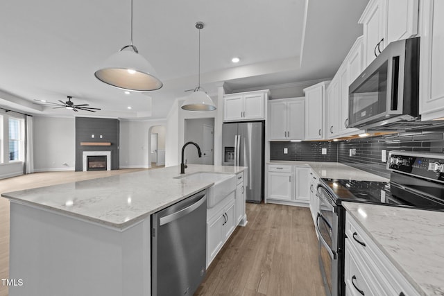 1319 Richfield Oaks Dr, Fuquay Varina, NC 27526 - kitchen featuring appliances with stainless steel finishes, a ceiling fan, light wood-style floors, white cabinetry, and a raised ceiling