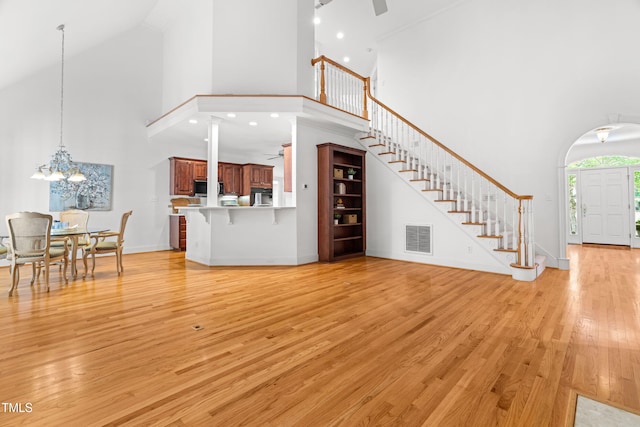 619 Baybush Dr, Raleigh, NC 27615 - unfurnished living room featuring a towering ceiling, stairway, light wood-type flooring, and a chandelier