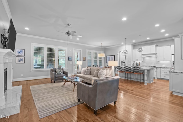 2121 Vecchio Ln, Apex, NC 27502 - living room featuring a ceiling fan, ornamental molding, recessed lighting, light wood-style flooring, and a fireplace