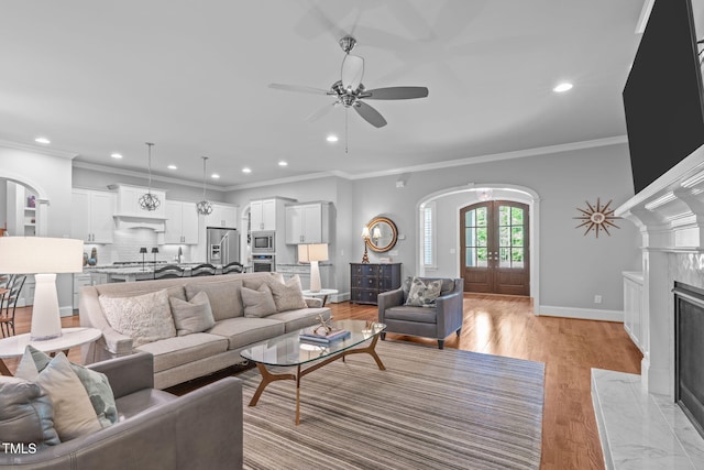 2121 Vecchio Ln, Apex, NC 27502 - living room featuring arched walkways, ceiling fan, recessed lighting, light wood-style floors, and a high end fireplace