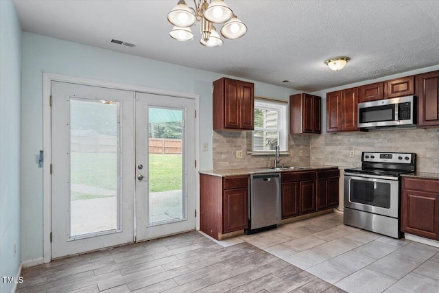 4709 Tyne Dr, Durham, NC 27703 - kitchen featuring appliances with stainless steel finishes, french doors, light wood-style flooring, and tasteful backsplash