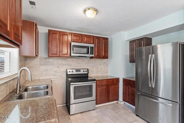 4709 Tyne Dr, Durham, NC 27703 - kitchen featuring appliances with stainless steel finishes, backsplash, light countertops, and a textured ceiling