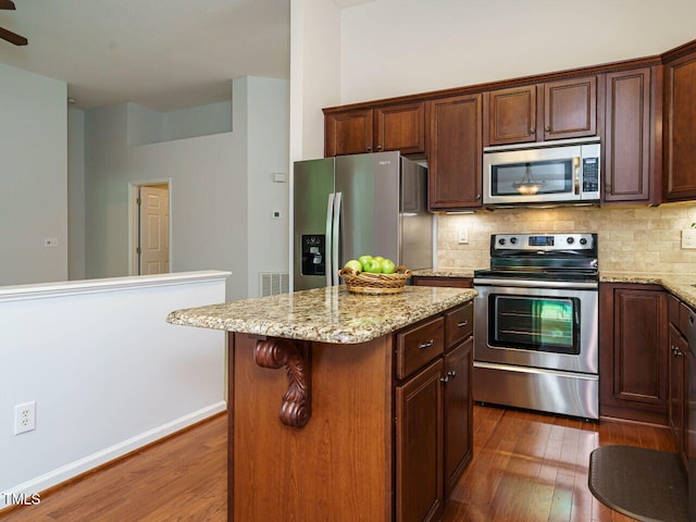 101 Lake Tillery Dr, Cary, NC 27519 - kitchen with appliances with stainless steel finishes, dark wood finished floors, a center island, and decorative backsplash