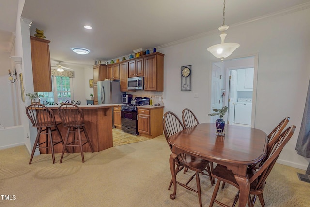 734 Crystal Forest Dr, Semora, NC 27343 - kitchen featuring appliances with stainless steel finishes, washer / clothes dryer, a kitchen breakfast bar, brown cabinetry, and crown molding