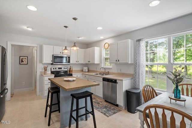 1990 Ferbow St, Creedmoor, NC 27522 - kitchen with appliances with stainless steel finishes, a center island, white cabinetry, a kitchen bar, and light countertops