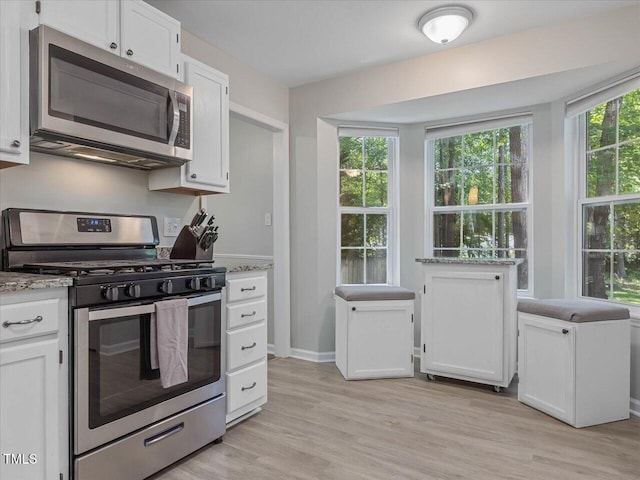 221 Antique Lace Way, Holly Springs, NC 27540 - kitchen featuring appliances with stainless steel finishes, white cabinetry, light wood-style flooring, and light stone counters
