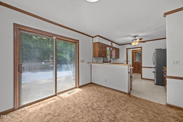 2382 Council Rd, Graham, NC 27253 - kitchen with freestanding refrigerator, a peninsula, a ceiling fan, ornamental molding, and light colored carpet