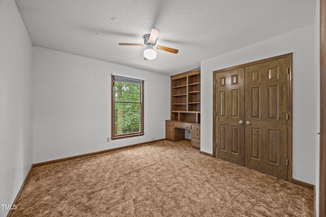 2382 Council Rd, Graham, NC 27253 - unfurnished bedroom featuring carpet floors, built in study area, a closet, a textured ceiling, and a ceiling fan