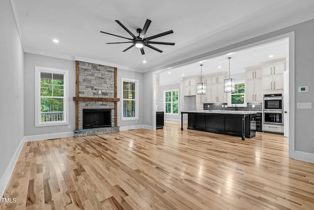 5504 Earle Rd, Raleigh, NC 27606 - living area with light wood finished floors, crown molding, a ceiling fan, recessed lighting, and a stone fireplace