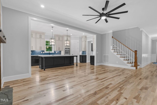5504 Earle Rd, Raleigh, NC 27606 - living room with light wood-style floors, crown molding, ceiling fan, stairs, and recessed lighting