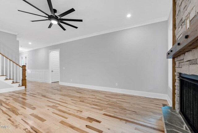 5504 Earle Rd, Raleigh, NC 27606 - unfurnished living room featuring a stone fireplace, crown molding, stairs, light wood-style flooring, and ceiling fan