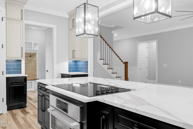 5504 Earle Rd, Raleigh, NC 27606 - kitchen featuring dark cabinetry, black electric cooktop, decorative backsplash, light wood-style floors, and crown molding