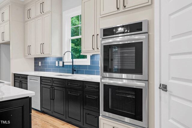 5504 Earle Rd, Raleigh, NC 27606 - kitchen with stainless steel appliances, dark cabinetry, light stone counters, and decorative backsplash