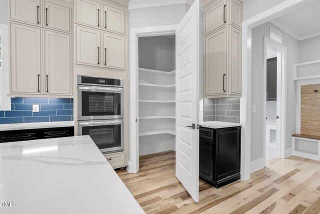 5504 Earle Rd, Raleigh, NC 27606 - kitchen featuring double oven, light wood-style floors, decorative backsplash, light stone counters, and ornamental molding