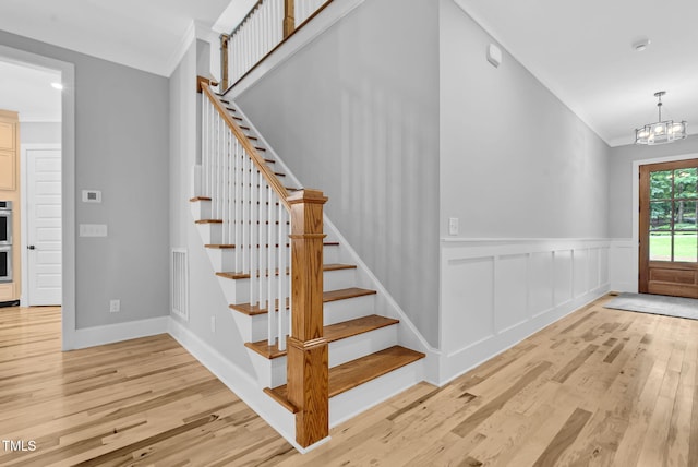 5504 Earle Rd, Raleigh, NC 27606 - foyer entrance featuring crown molding, light wood finished floors, stairway, a chandelier, and wainscoting