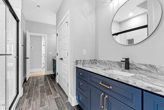 5504 Earle Rd, Raleigh, NC 27606 - bathroom featuring vanity, a stall shower, and wood finish floors