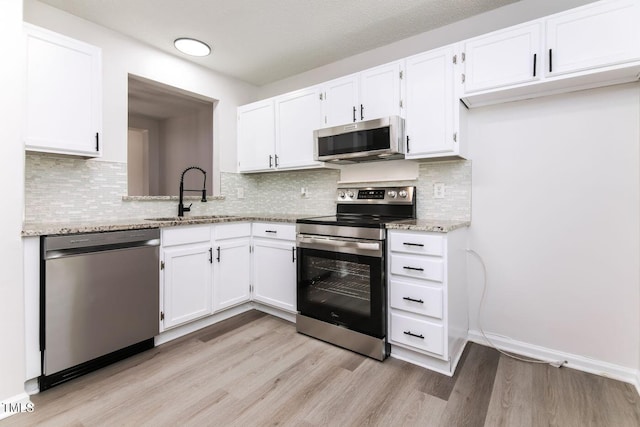404 Shannonford Ct, Wake Forest, NC 27587 - kitchen featuring appliances with stainless steel finishes, a sink, light wood-style flooring, white cabinetry, and light stone counters